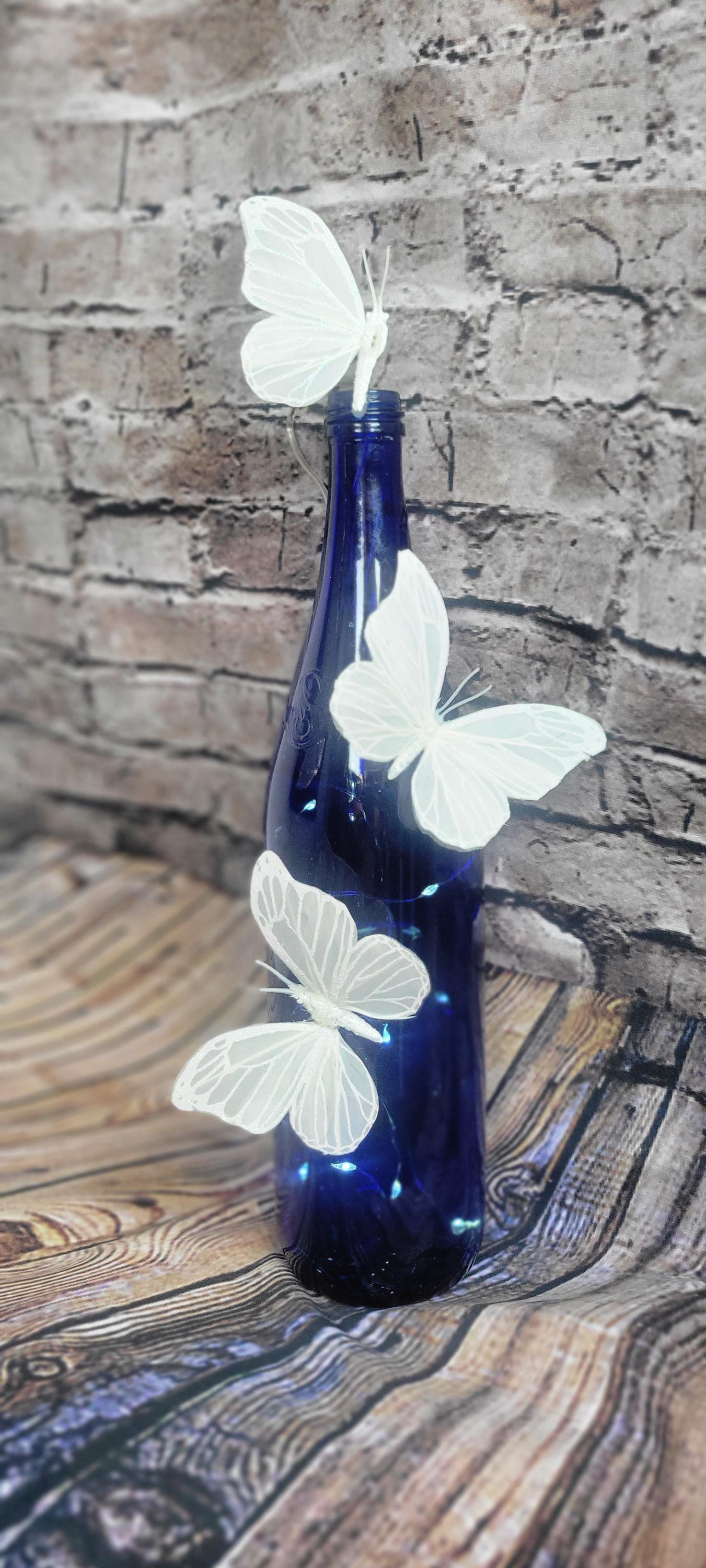 Cobalt blue wine bottle electric LED lights with white butterflies table decor centerpiece