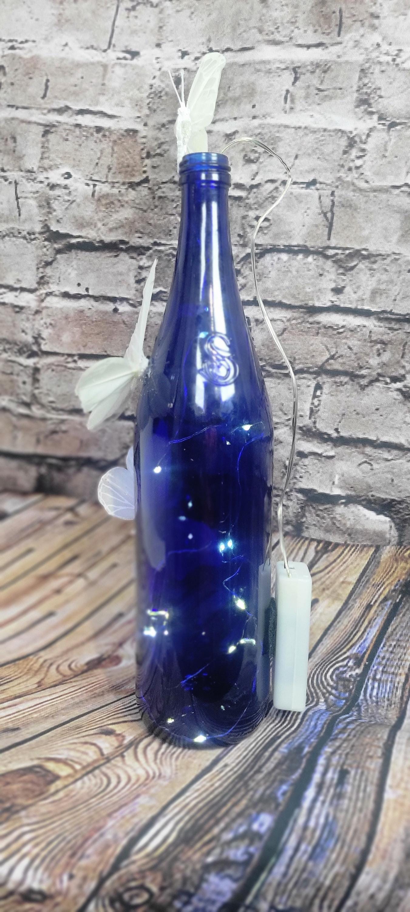 Cobalt blue wine bottle electric LED lights with white butterflies table decor centerpiece