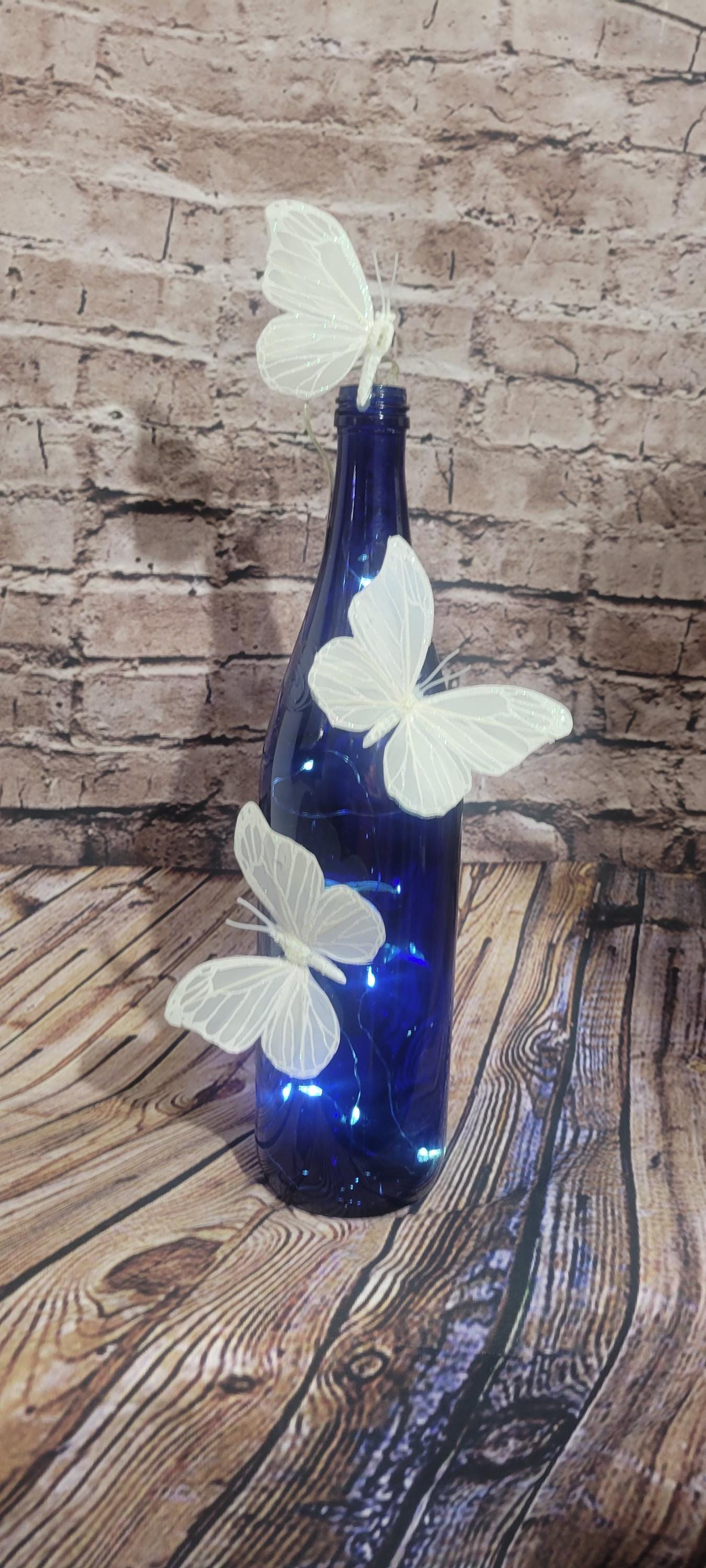 Cobalt blue wine bottle electric LED lights with white butterflies table decor centerpiece